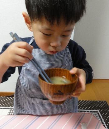 お姉ちゃんが作ったおみそ汁を飲む弟